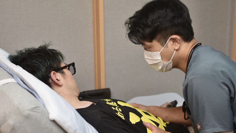 ご自宅のベッドサイドで丁寧にケアを行う訪問看護師