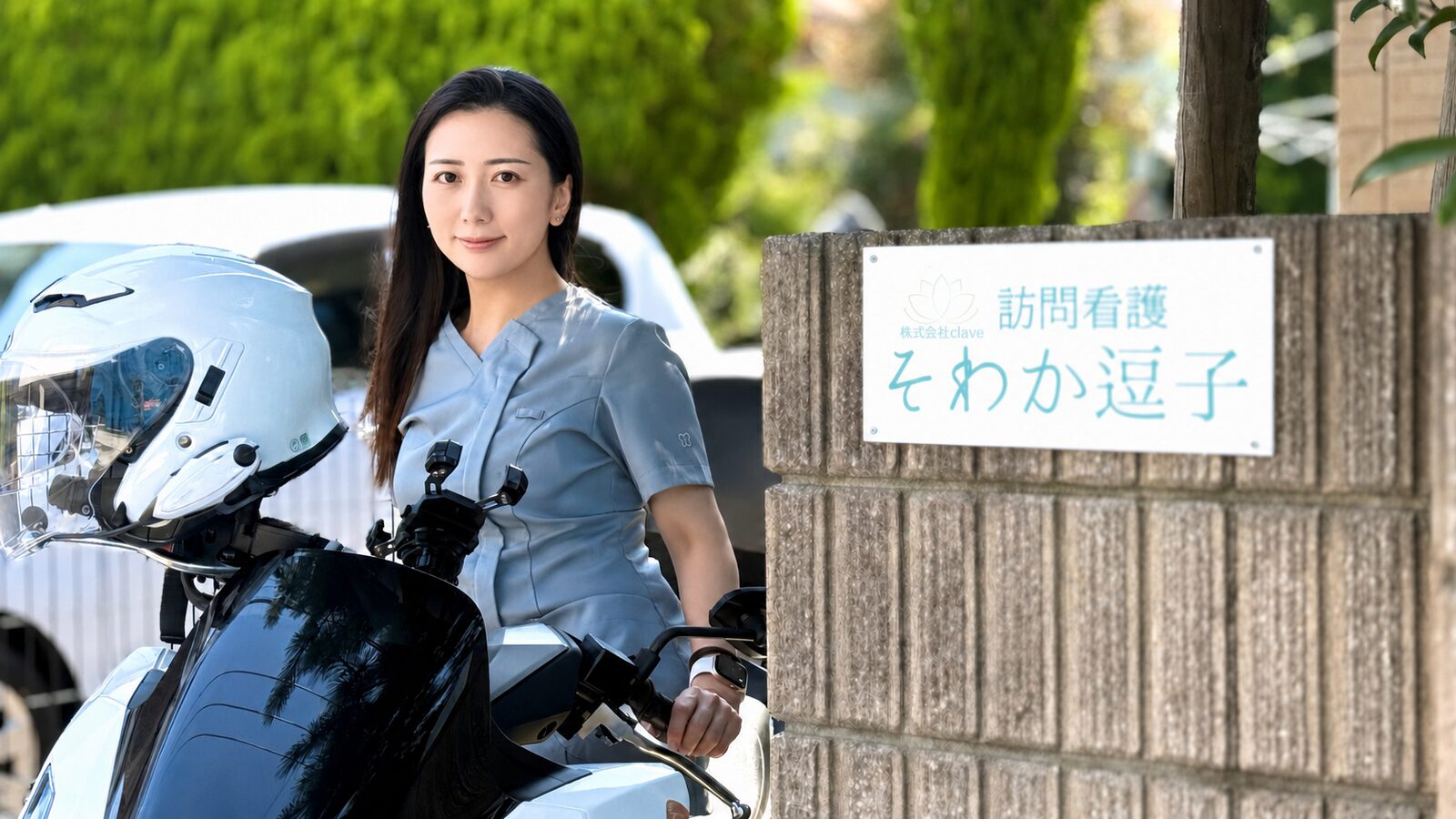 そわか逗子の看板前でバイクにまたがる訪問看護師